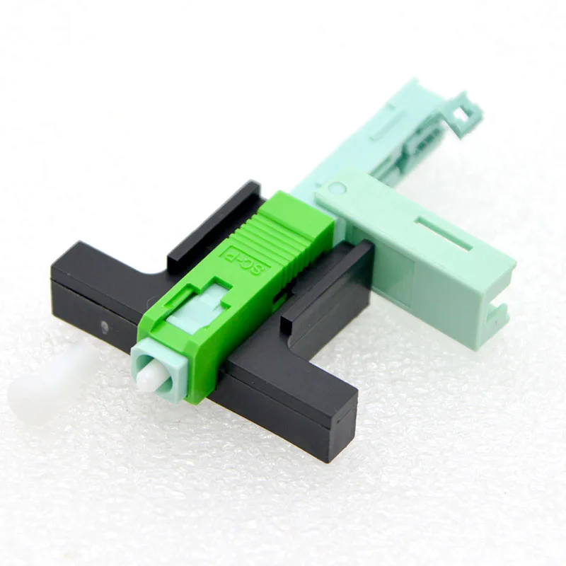 Un objeto de plástico verde y negro está sobre un fondo blanco.