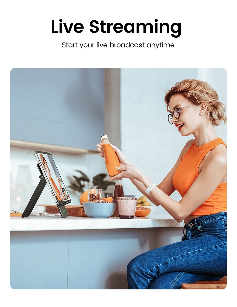 Una mujer está sentada en una mesa con una computadora portátil y una botella de jugo.