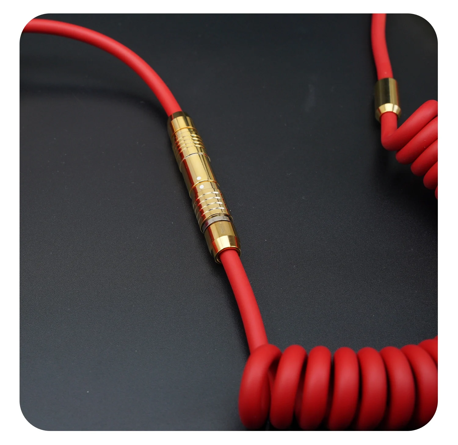 Un cordón rojo con un conector de oro sobre un fondo negro