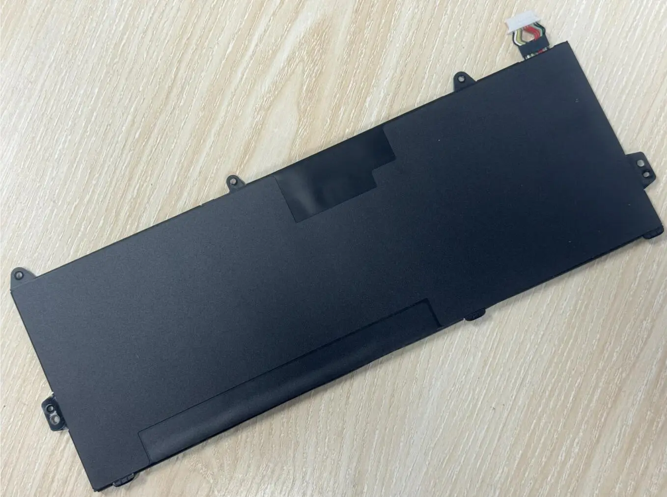 Un dispositivo electrónico negro se encuentra en una mesa de madera