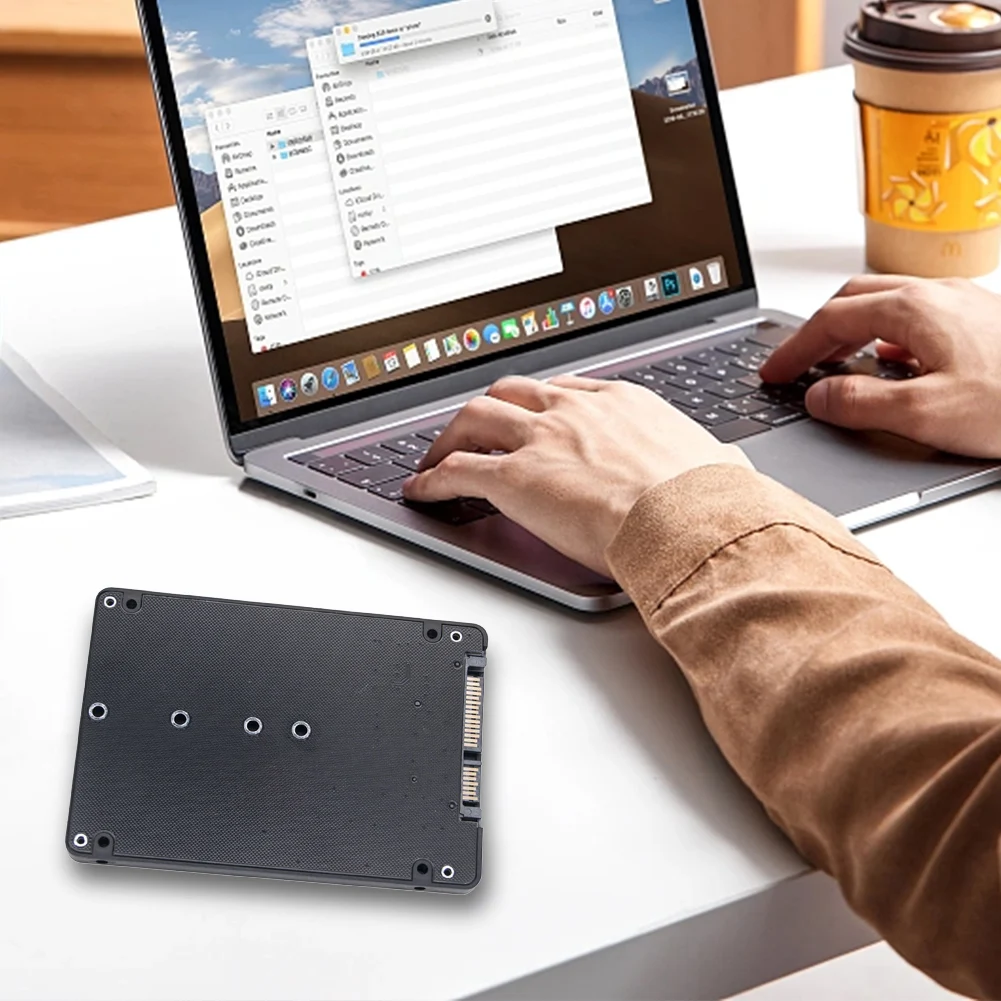 Una persona está escribiendo en una computadora portátil con una tableta frente a ellos