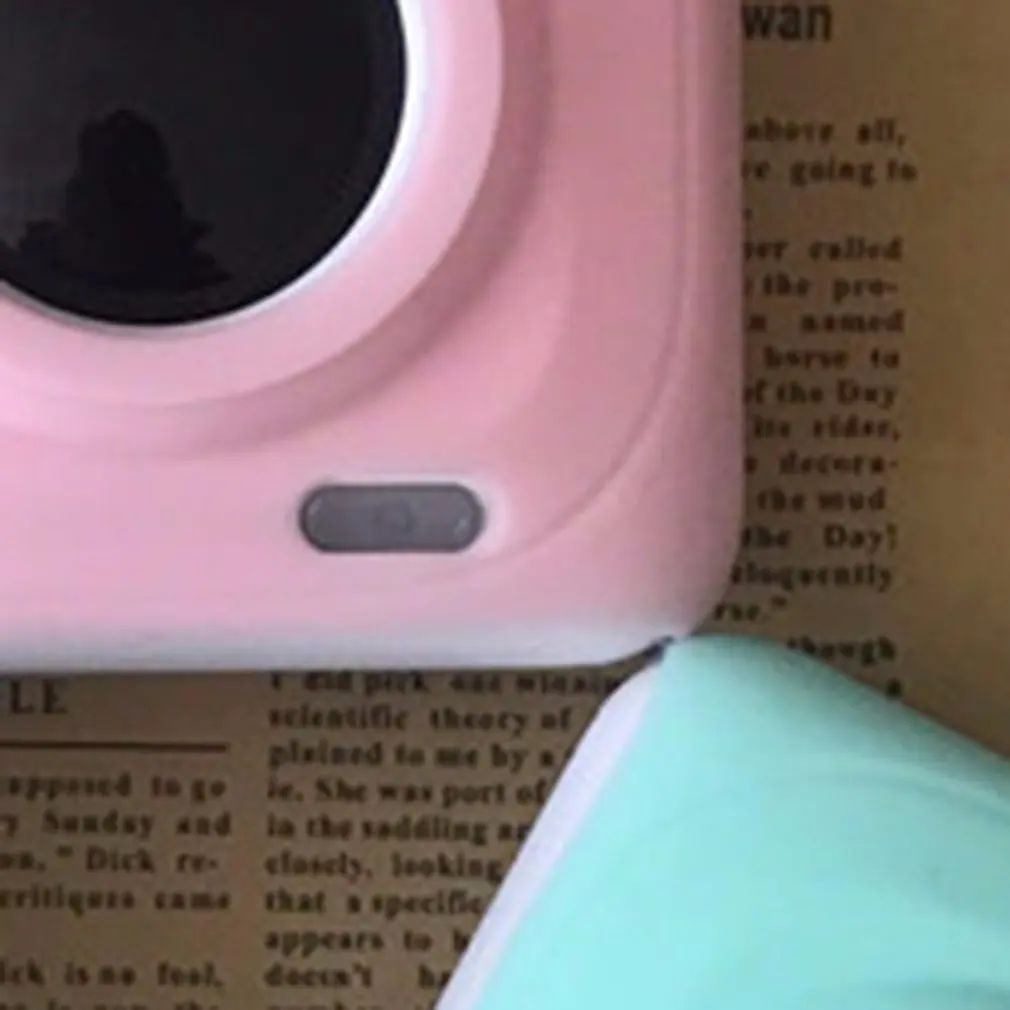 Una cámara rosa y verde está sentada encima de un periódico