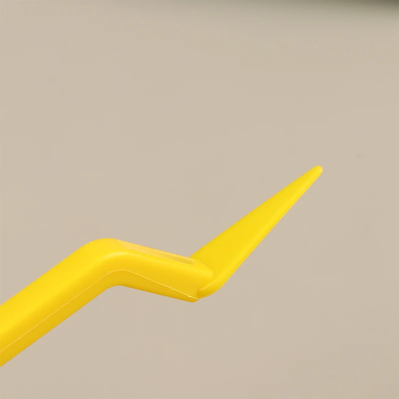 Un objeto de plástico amarillo está sobre un fondo gris