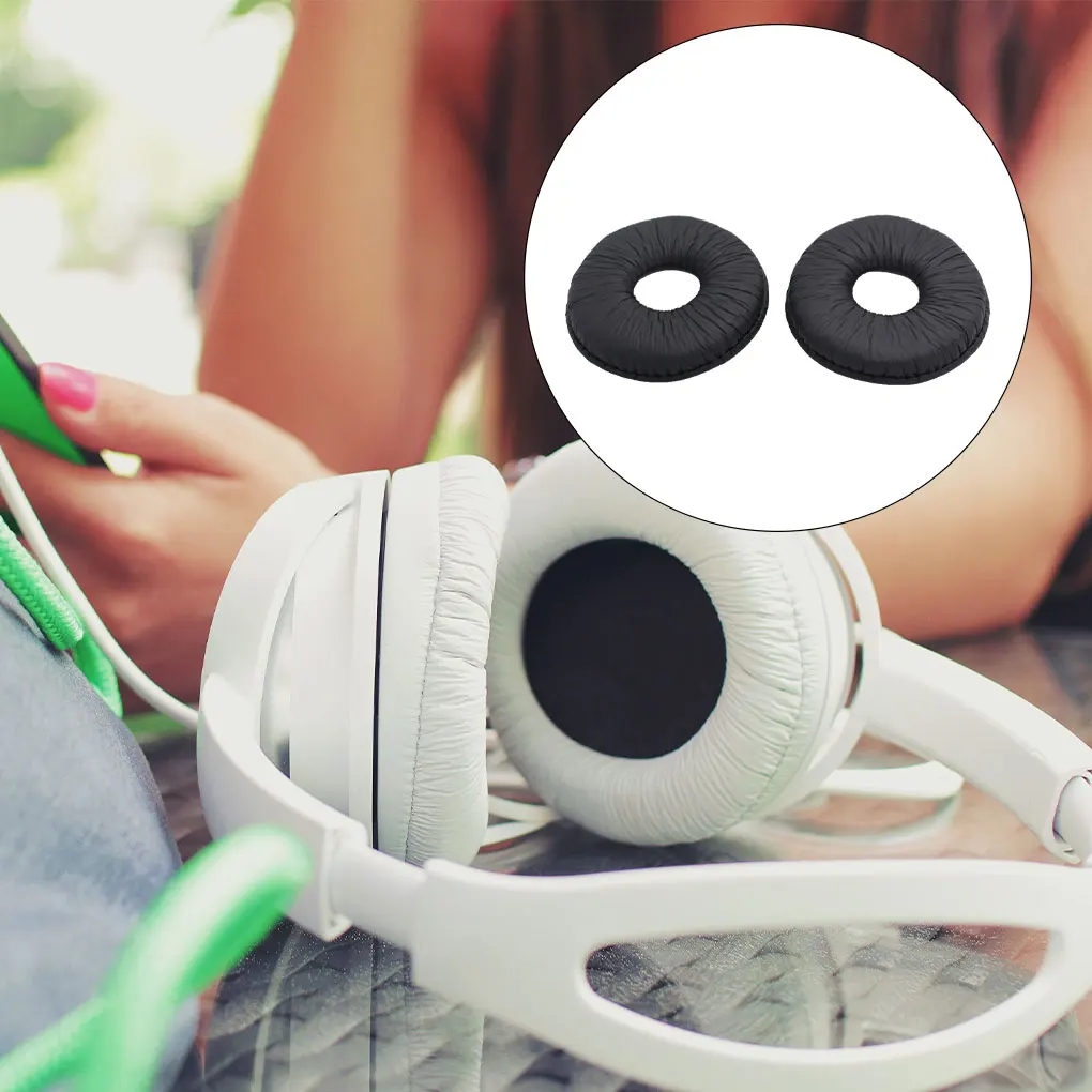 Una mujer sostiene un teléfono celular y los auriculares están sobre la mesa.