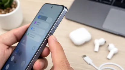 Primer plano del boton lateral de un movil Android premium sobre una mesa con cable USB-C.