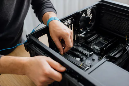Técnico instalando un SSD M.2 con pulsera antiestática en un ordenador.