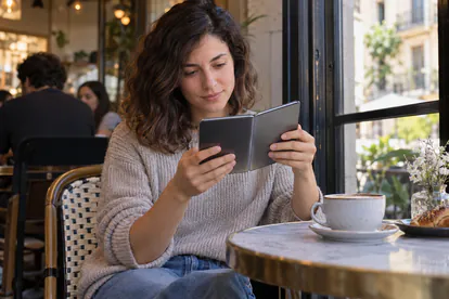 Usuario lee en la pantalla interior de un teléfono plegable en una cafetería